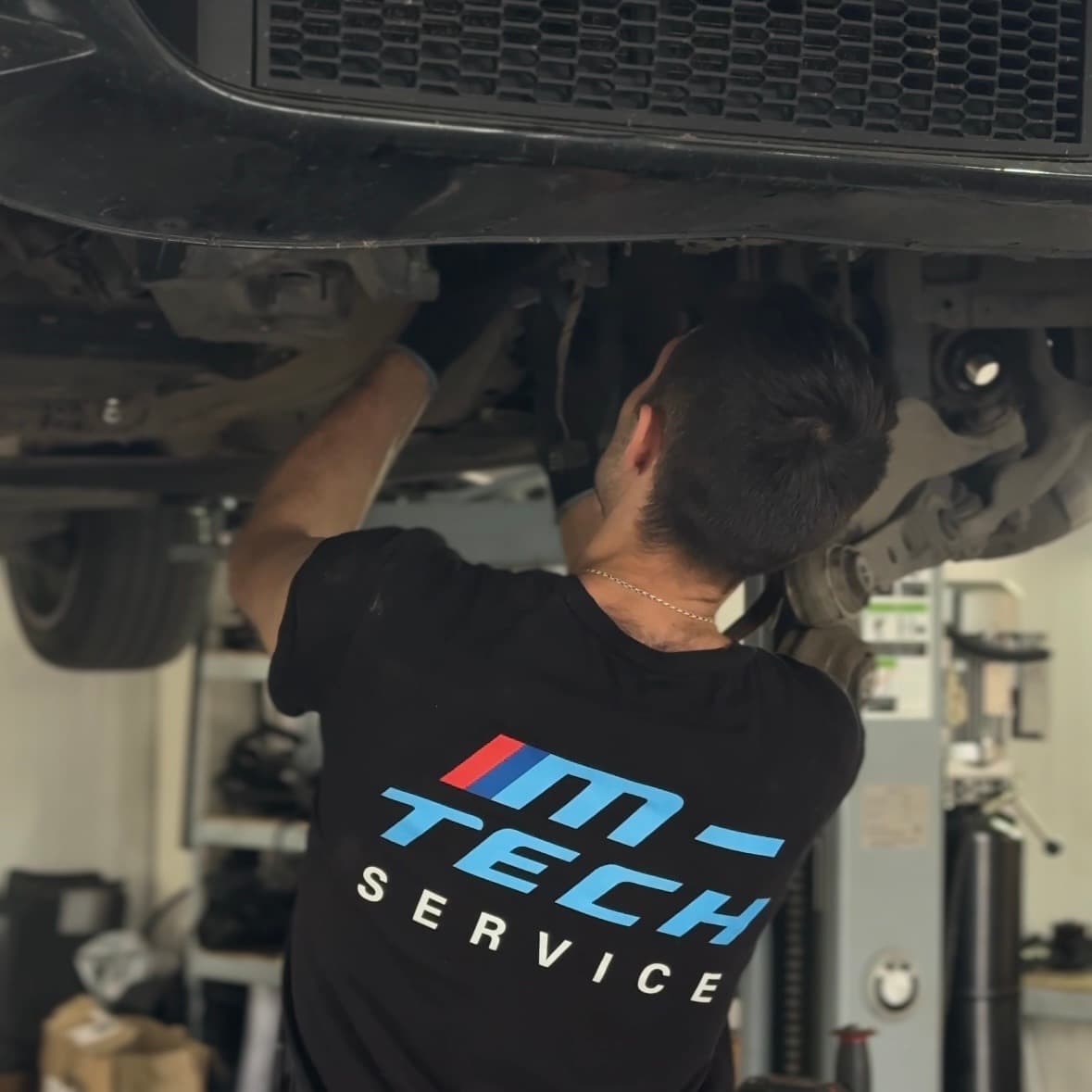 Майстер M-Tech працює під авто на підйомнику